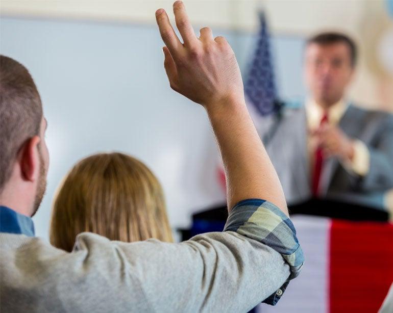 An advocate for older adults raises his hand at a town hall.
