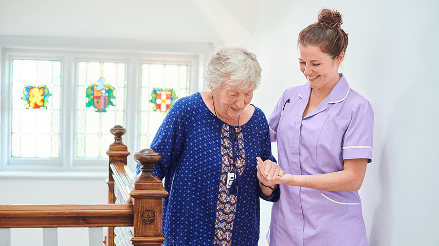 direct care worker helping older woman on stairs
