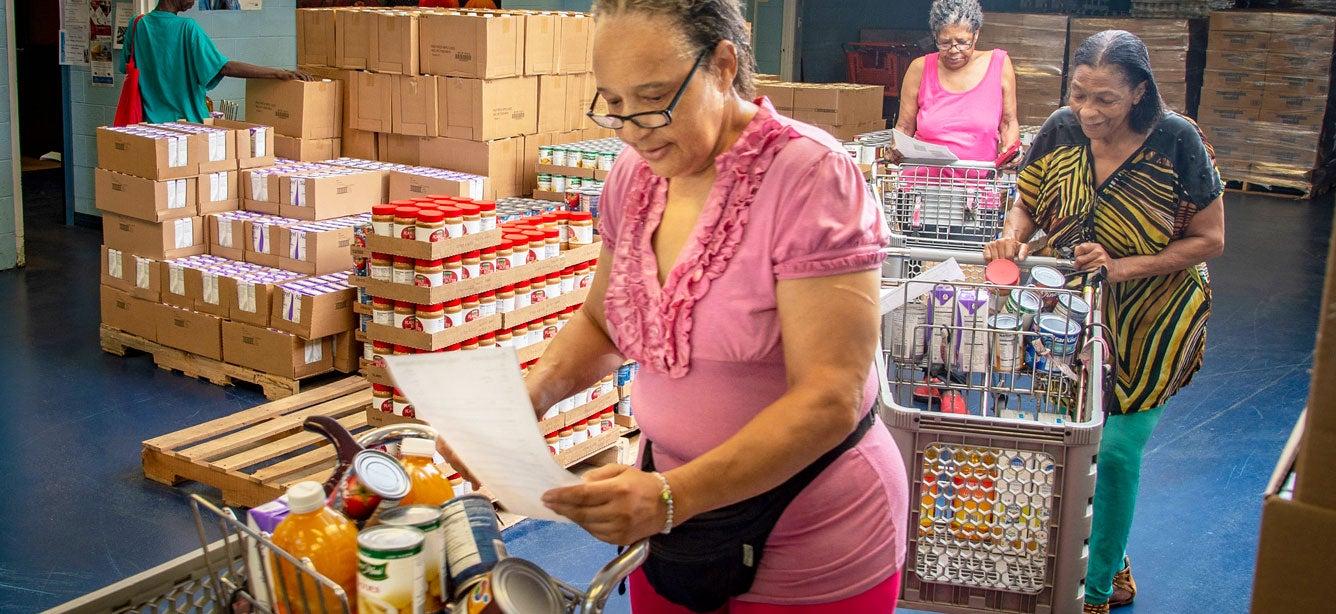 Four senior Black women in Detroit, Michigan shop the Commodity Supplemental Food Program (CSFP), selecting the foo