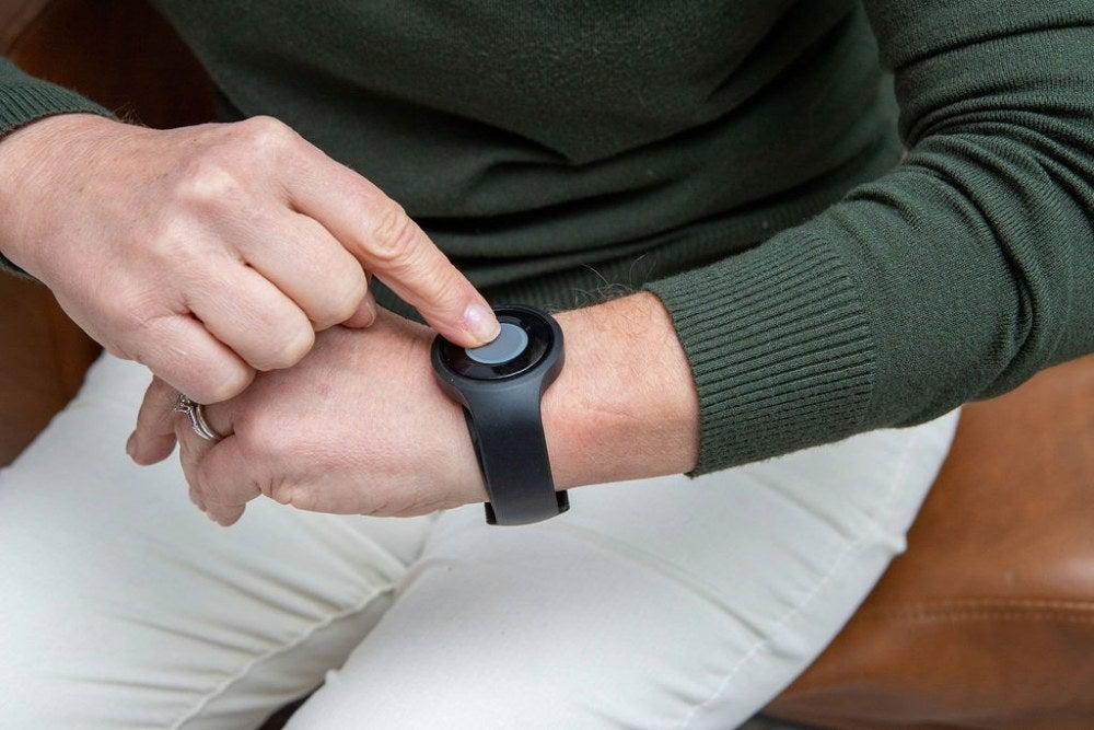 A person wearing a medical alert wristband pressing the help button