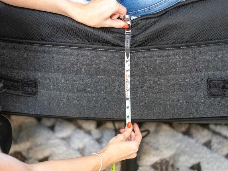 Someone measures how far the Nolah Evolution Luxury Firm mattress sinks when a tester sits on the edge.