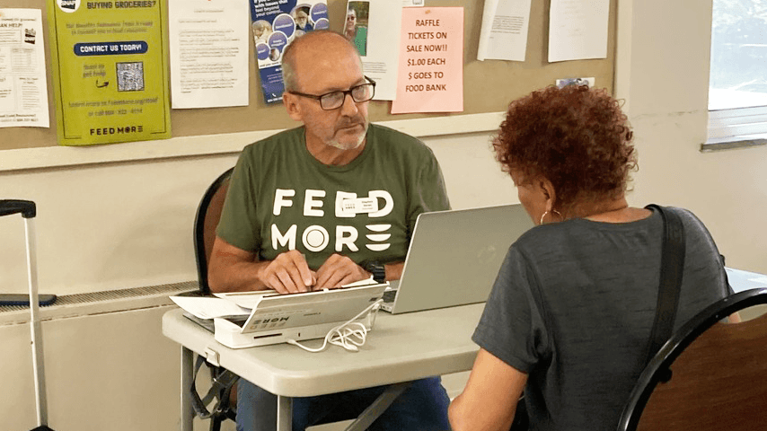 Benefits counselor from Feed More, based out of Virginia, is helping a senior Black woman apply for food assistance benefits at a local senior center.