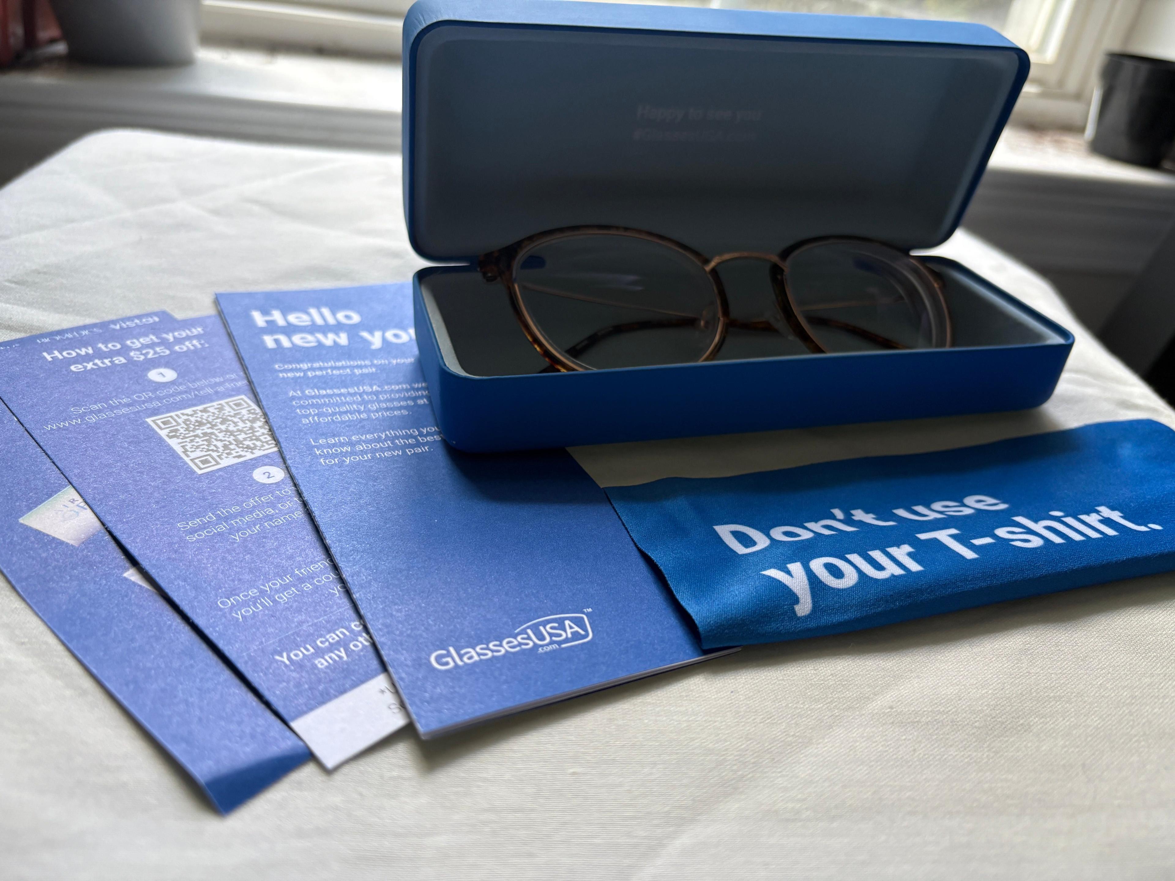 A blue GlassesUSA glasses case, three coupons, and a sassy lens cloth