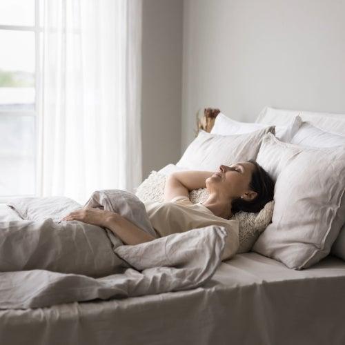 A woman relaxes on a bed with tan sheets