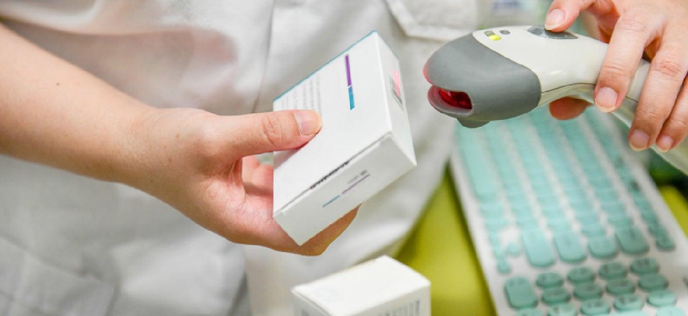 Pharmacist scans prescription drug box.