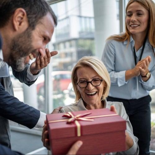 Business team surprising colleague with a gift in the office