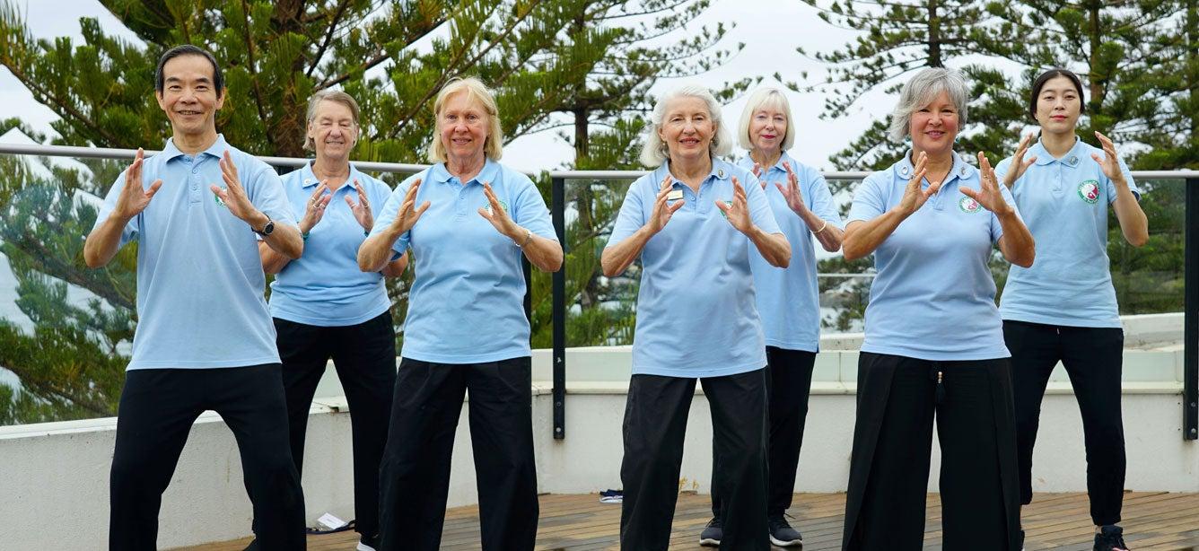 Dr. Paul Lam and other older adults participate in a sun style tai chi workshop together outside.