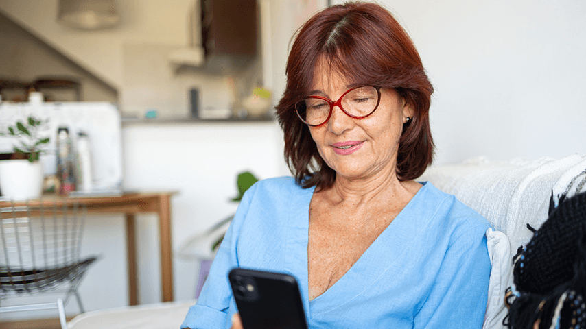 smiling woman wearing glasses and looking at cellphone