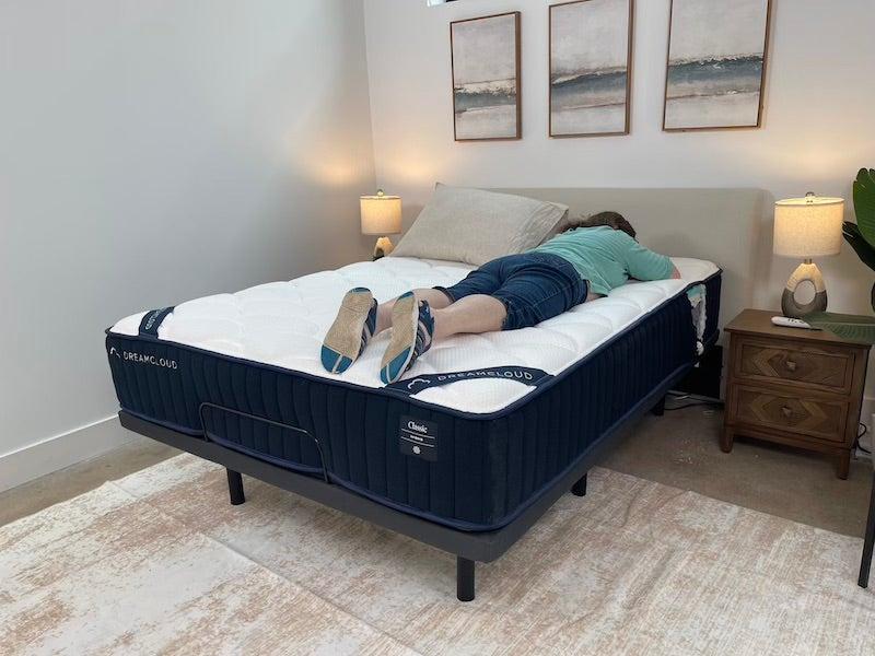A female tester rests on her stomach on the DreamCloud Classic Hybrid