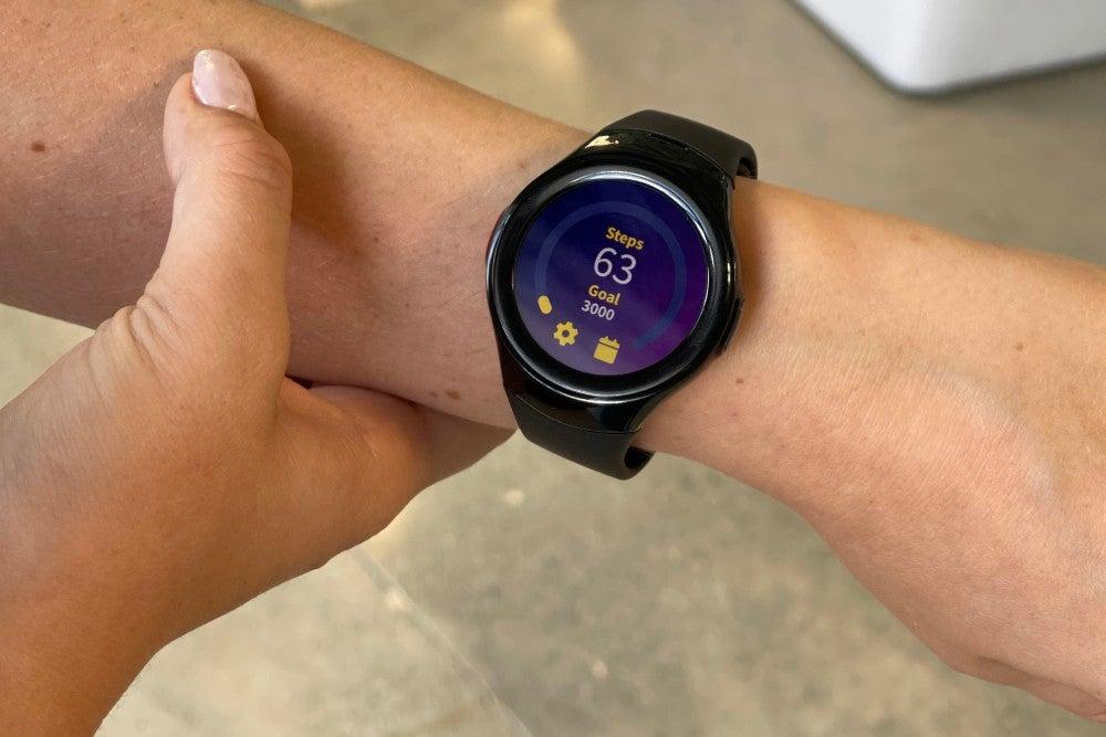 Woman wears smartwatch on her left wrist, showing the watch face