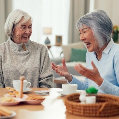 Two older women share a conversation and a laugh
