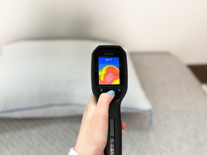 A tester points a thermal gun at the Nectar Tri-Comfort pillow to measure temperature increase