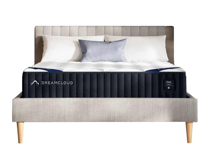 The DreamCloud Classic Hybrid without sheets, in front of a padded grey headboard