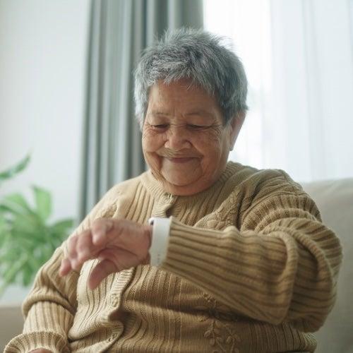 A woman checks her medical alert system smartwatch and smiles