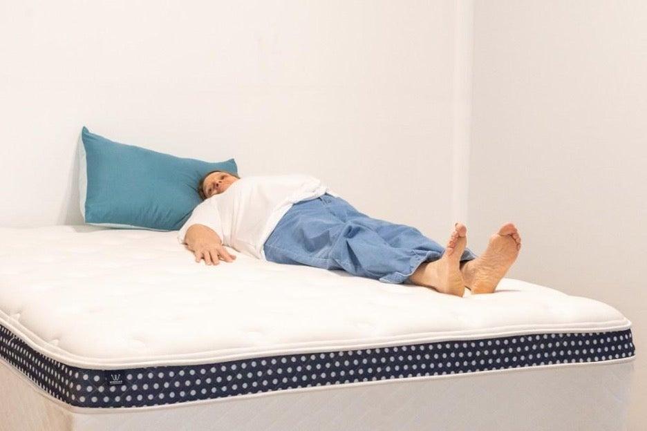 A woman lies on her back on the WinkBed Plus mattress.