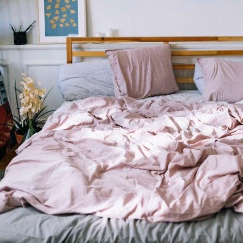 An unmade bed with a pink duvet cover on it