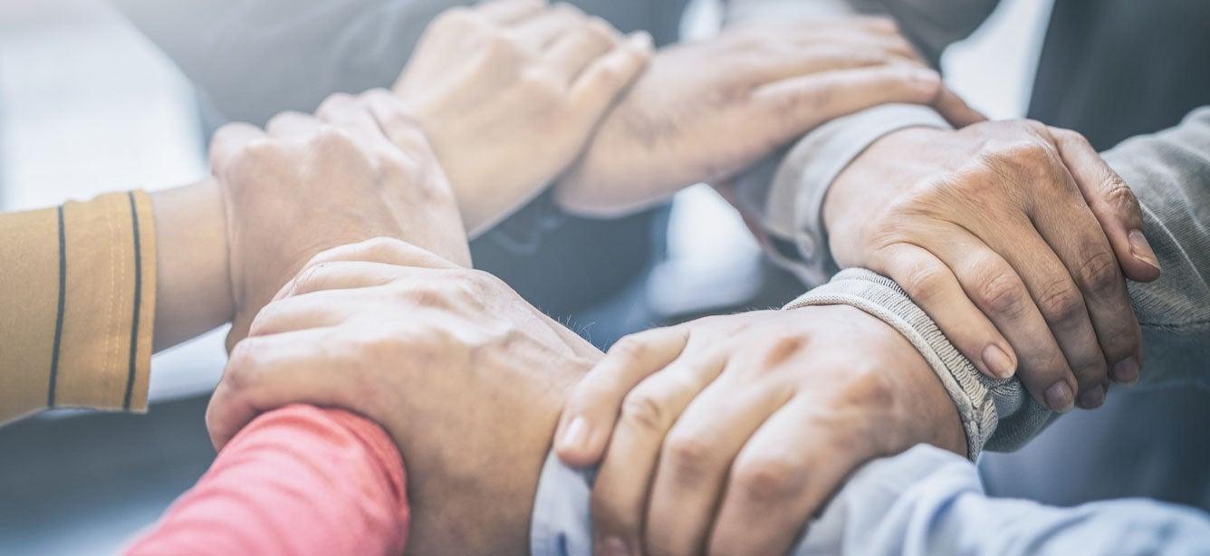 A group of aging services professionals are holding hands in a circle, indicating strength in numbers.