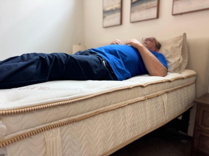 A man lies on his back on the Saatva Latex Hybrid mattress