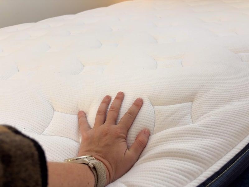 A female tester places her hand on the cover of the Silk & Snow Hybrid to demonstrate sinkage