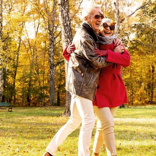 A couple walking in a park, holding each other and smiling.