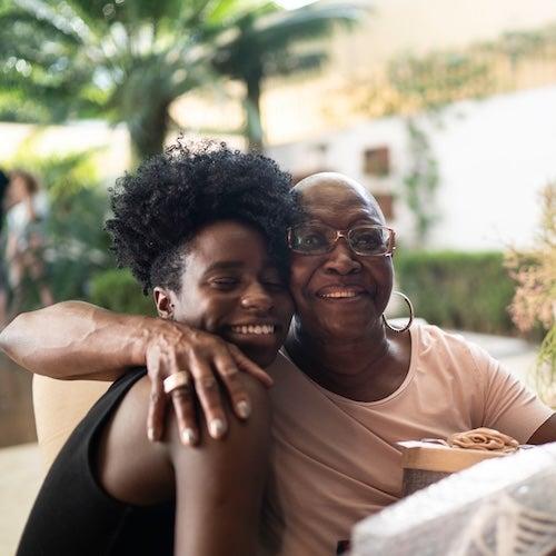 An older woman holding a gift and hugging a younger woman