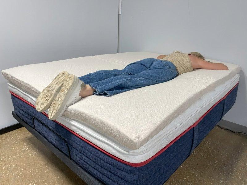 A woman lying on her stomach on the Avocado mattress topper