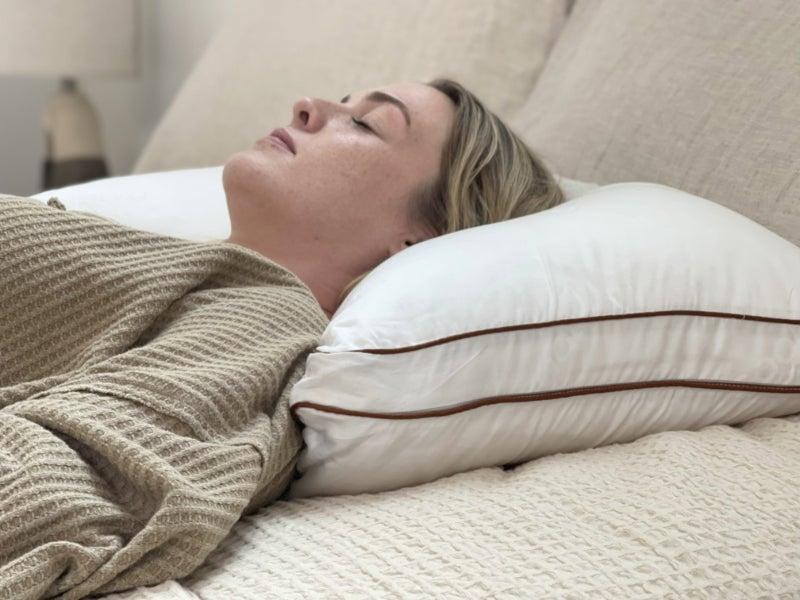 A woman sleeps on her back on a Saatva Latex pillow.