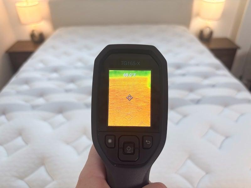 A heat gun pointed at the Leesa Sapira Chill hybrid mattress reads 69 degrees