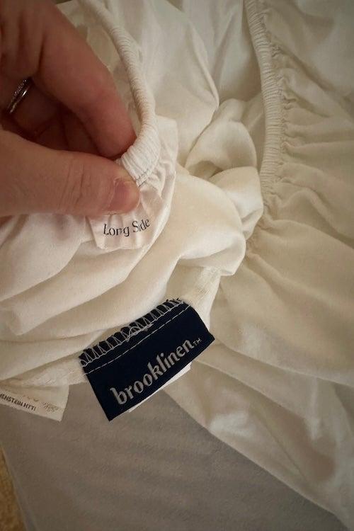 A label inside the Brooklinen Luxe Sateen Core sheet says “long side”