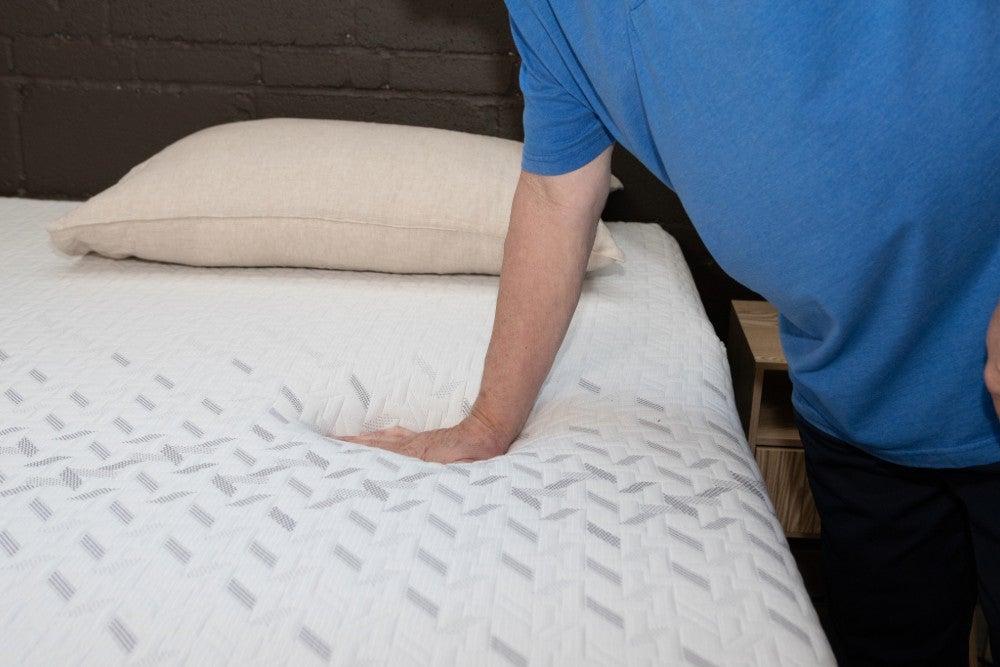 A man’s hand pushing down on the top of the Nectar Premier Memory Foam
