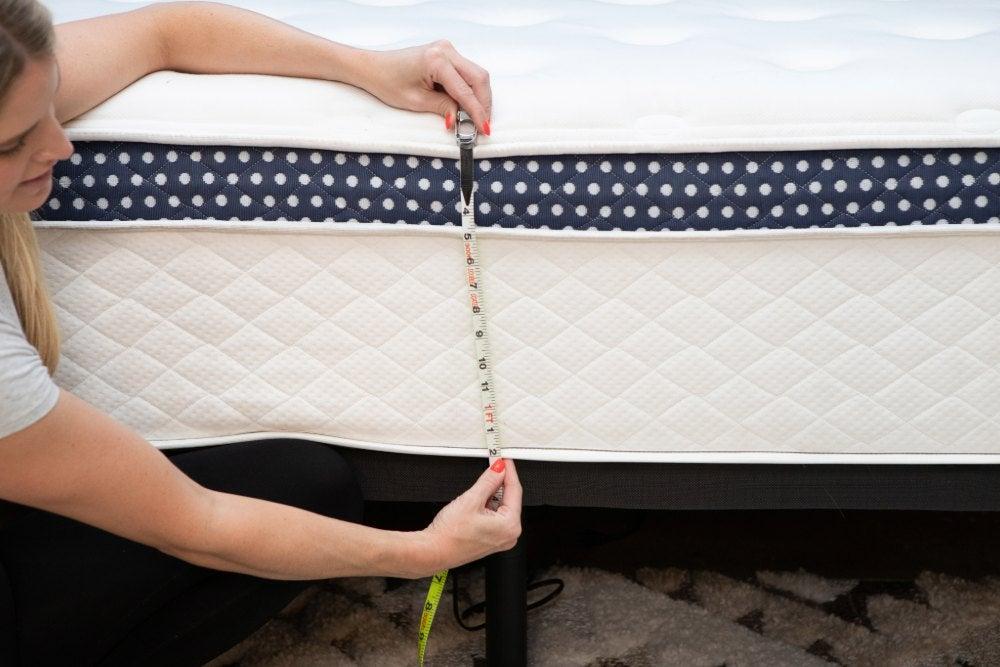 Woman uses a tape measure to record the WinkBed Plus mattress’ height