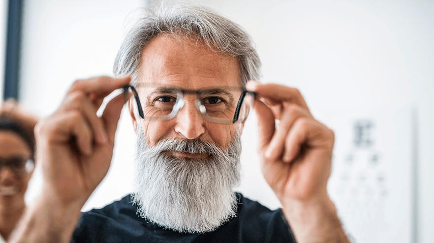 man with gray beard holding eyeglasses