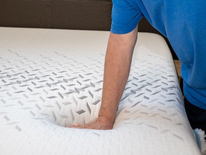 A hand pressing into the top of the Nectar Premier Hybrid mattress
