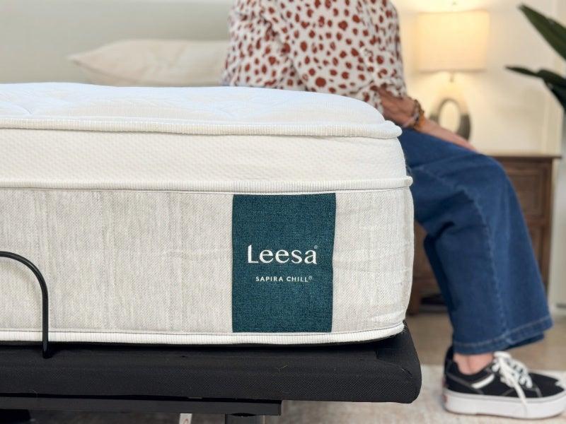A woman sits on the edge of the Leesa Sapira Chill hybrid mattress