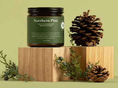 Northern Pine candle in a jar with a dark green label, displayed with pinecones.