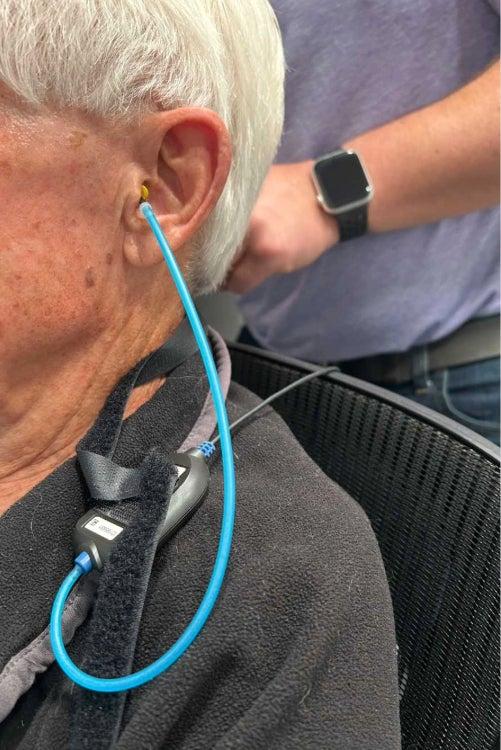 man undergoing a hearing test with tube in left ear