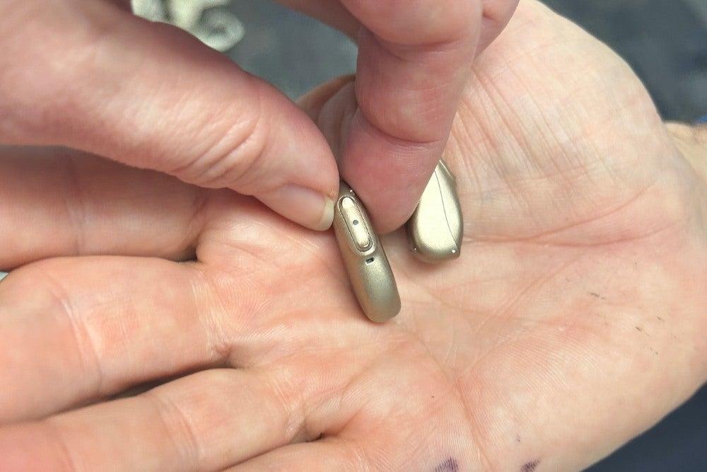 gold Phonak hearing aid in woman's hands