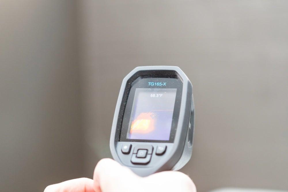 A person holding a temperature sensing gun