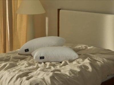 Two white Silk & Snow pillows on a beige cover on a bed