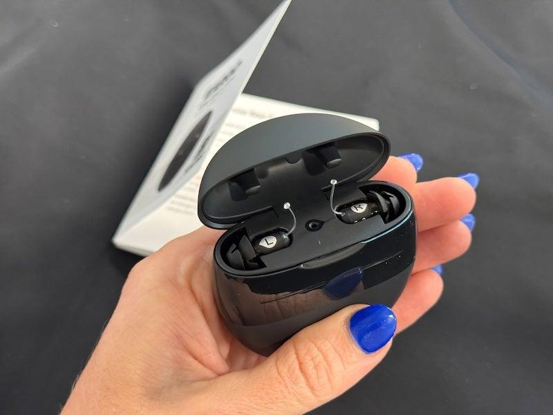 Woman with blue nail polish holds Eargo 8 hearing aids in their black portable charging case