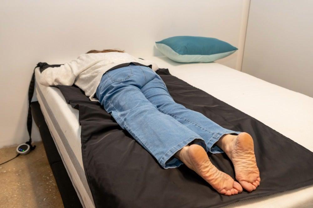 A woman lying on her stomach on top of a pressure map laid over the Helix Plus mattress