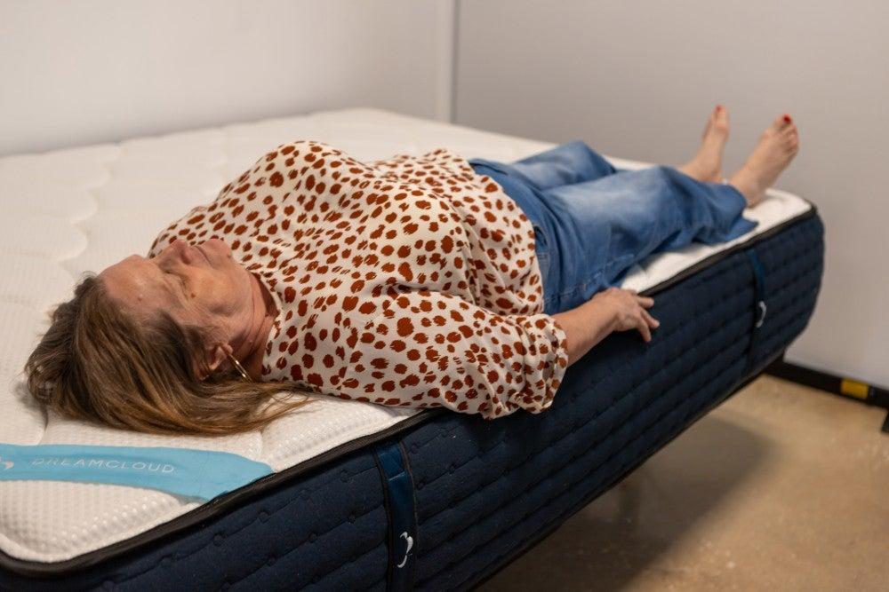 Woman lies on edge of DreamCloud mattress on her back