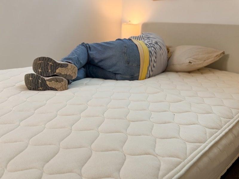 A woman lies on her side on the WinkBed EcoCloud mattress.