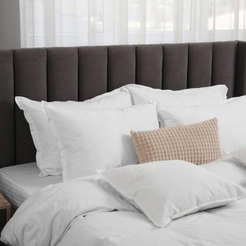 A comfortable-looking bed with white sheets and fluffy pillows
