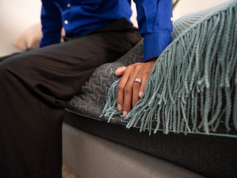 The side of the Tuft & Needle Mint Hybrid mattress compresses under a seated man's weight