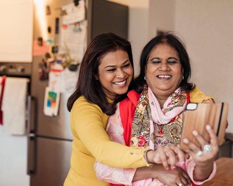 A senior Bangladeshi woman is being hugged by her daughter while they're taking a selfie.