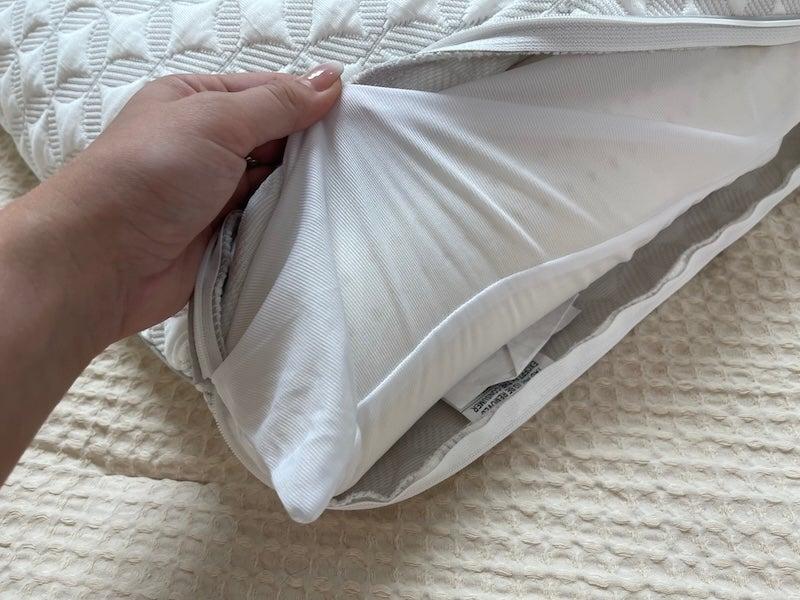 A hand touches the latex core of the unzipped Brooklyn Bedding Talalay Latex pillow