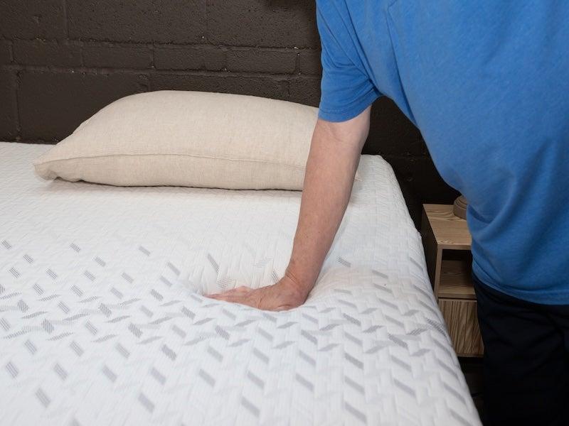 A man pushes down on the Nectar Classic Memory Foam mattress