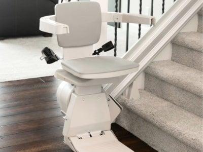 A Bruno stair lift at the base of a set of indoor stairs