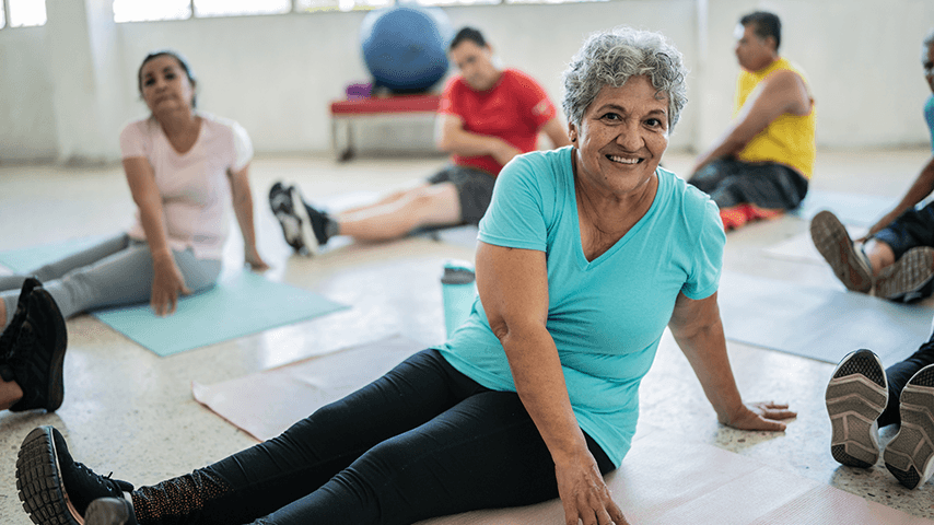 smiling older adult woman on floor mat in yoga class
